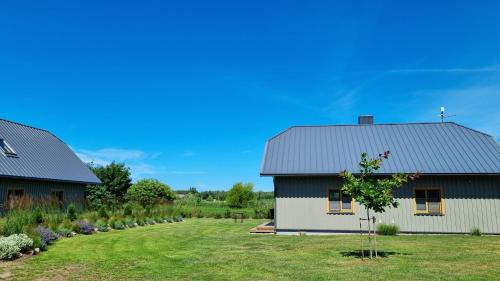 a white house with a gray roof and a yard at Smiltinas in Nidden
