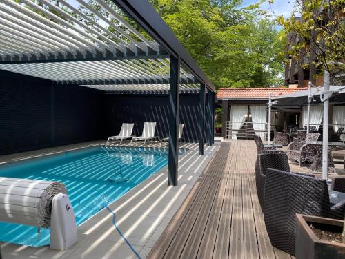 an outdoor swimming pool with a pergola and a swimming poolvisor at Enzo Hôtels Diane - Logis Amnéville in Amnéville