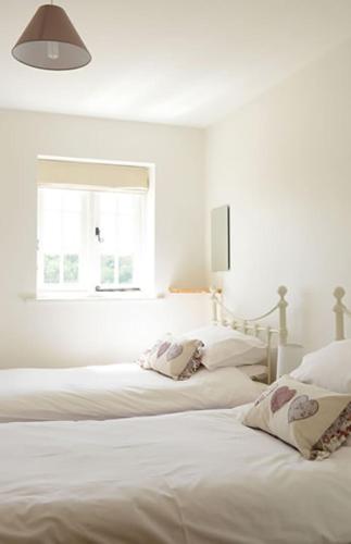 2 Betten in einem weißen Zimmer mit Fenster in der Unterkunft Mill Lane Farm Holiday Cottages in Lyndhurst