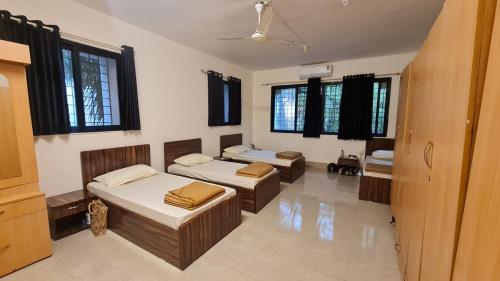 a room with two beds and a couch and windows at Rostel Backpackers Hostel in Pune