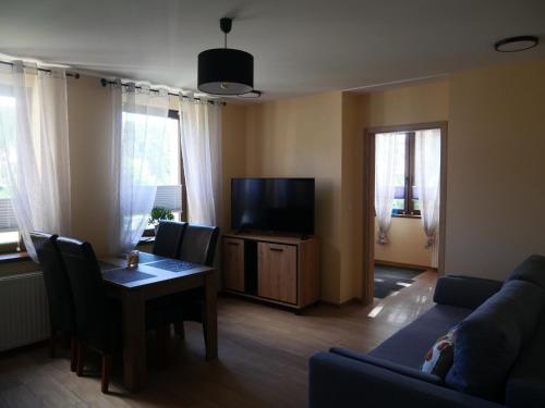 a living room with a couch and a table and a tv at Apartament Karamba in Szklarska Poręba