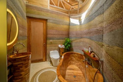 a bathroom with a wooden tub and a toilet at Ulaman Eco Luxury Resort in Tabanan
