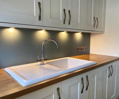 a kitchen with a white sink in a kitchen at Ivy Coastal Cottage in Caister-on-Sea