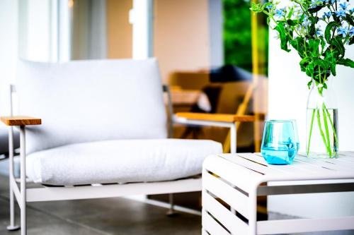 a white chair and a table with a vase on it at Aqua Blu Hotel in Bad Füssing