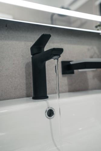 a black faucet with water coming out of it at Mia Marine Rooms in Himare