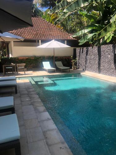 卡朗阿森的住宿－Rumah Kelapa Villa Alami，一个带遮阳伞和椅子的游泳池