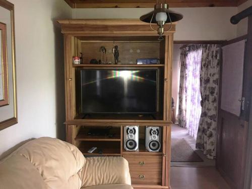 a television in a wooden entertainment center with speakers at Sedgefield Lagoon Hideout - Kingfisher Drive in Sedgefield
