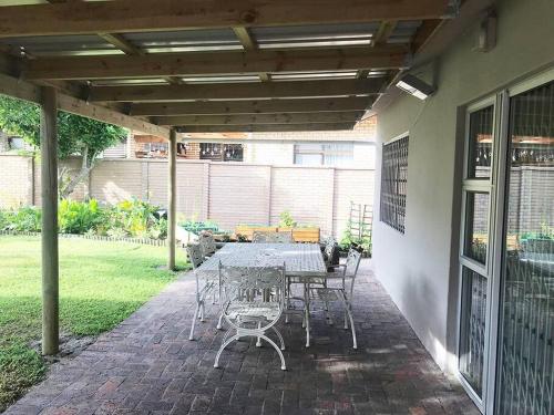 a patio with a table and chairs under a pergola at Sedgefield Lagoon Hideout - Kingfisher Drive in Sedgefield