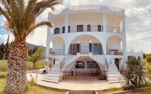 un gran edificio blanco con escaleras y una palmera en Magic house at halkida 1m from the beach! en Chalkida