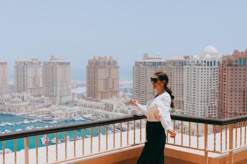 Eine Frau steht auf einem Balkon mit Stadtblick in der Unterkunft Sedra Arjaan by Rotana in Doha