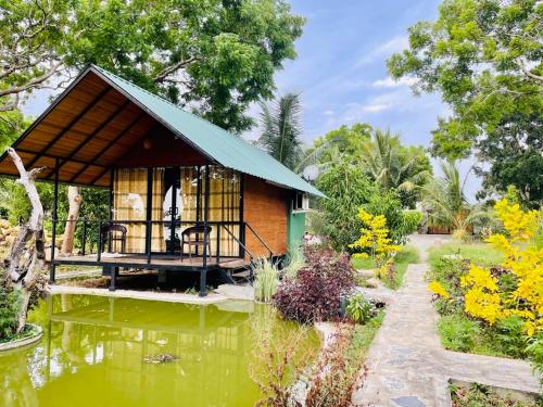 a small house with a pond in front of it at Kaaya Eco Resort Yala in Tissamaharama