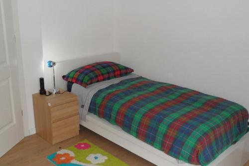ein Schlafzimmer mit einem Bett mit einer karierten Decke und einem Nachttisch in der Unterkunft CASA FLAMINIA in Pesaro
