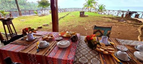 a table with food and a view of the ocean at Gombela Ecolodge and Farming in São Tomé