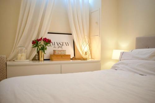 Un dormitorio con una cama blanca y una ventana con flores en Cozy 1 Bedroom Home near the City Centre, en Edimburgo