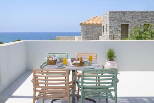 a table and chairs on a balcony with the ocean at Callisto Seaside Homes & Suites in Marathopolis
