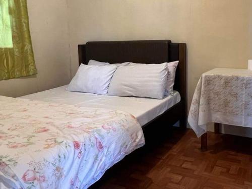 1 cama con sábanas blancas y cabecero negro en Serenity House en Baguio