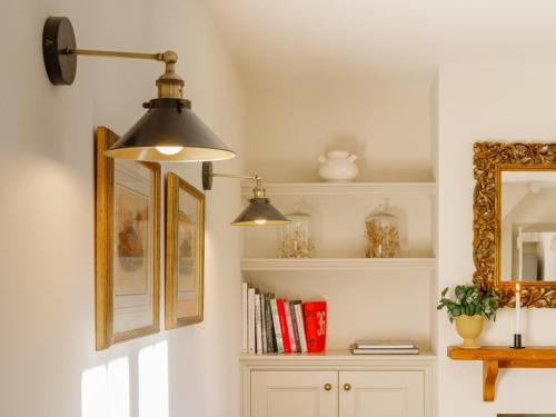 a room with two lights and a shelf with books at Beehives Cottage at Woodhall Estate in Hertford