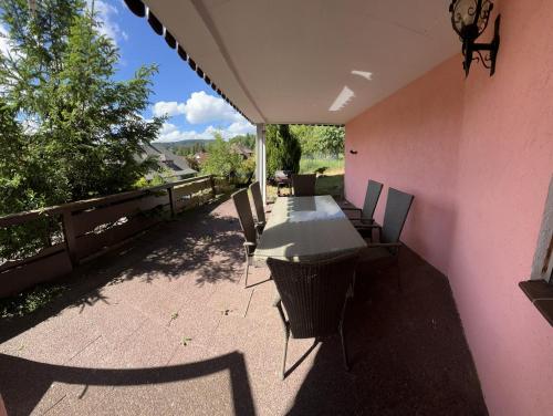 een patio met een tafel en stoelen aan een roze muur bij Ferienhaus Samy in Feldberg