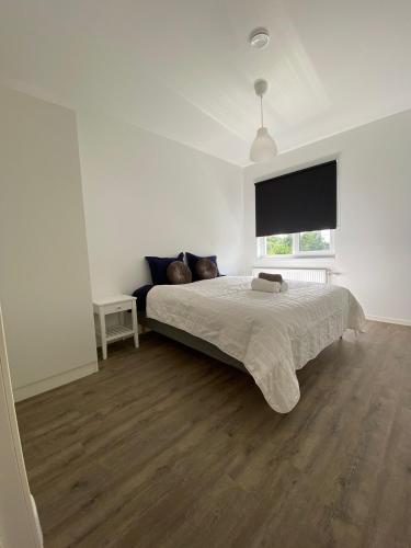 a white bedroom with a bed and a window at Solberga lägenhetshotell in Köpingsvik