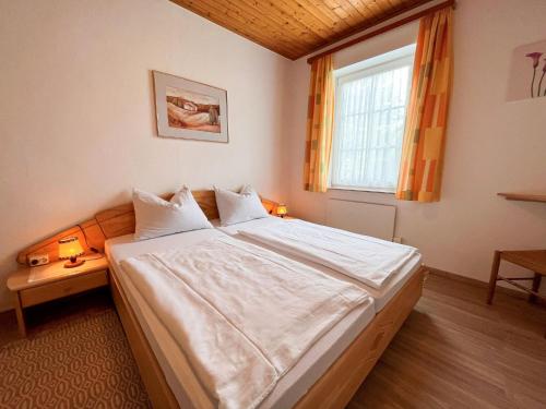 a bedroom with a large bed with white sheets and a window at Holiday Home Wiegele by Interhome in Aich