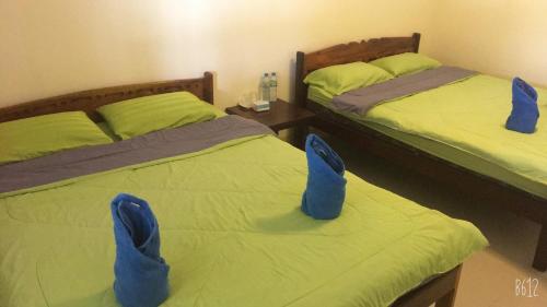 two beds with blue shoes on them in a room at Baan Dongsak River view in Sangkhla Buri