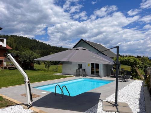 einen Pool mit Sonnenschirm neben einem Haus in der Unterkunft Apartment Frank-2 by Interhome in Feldkirchen in Kärnten