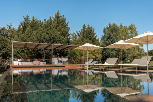 a swimming pool with two umbrellas and chairs at Vale Do Manantio in Moura