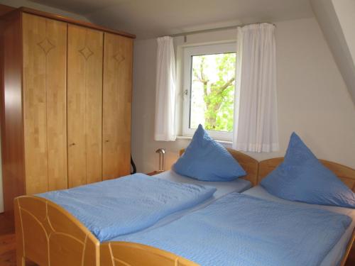 a bedroom with two beds with blue pillows and a window at Apartment Landhaus Mahnhamm-2 by Interhome in Wiarden
