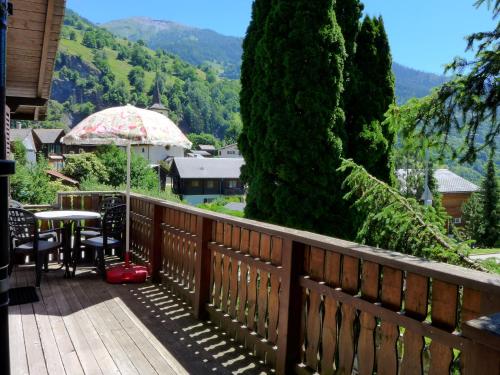 a wooden balcony with a table and an umbrella at Chalet Zur Säge by Interhome in Albinen