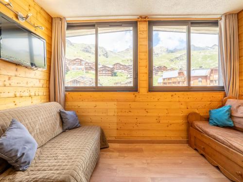 a living room with a couch and two windows at Apartment Les Cimes de Caron-7 by Interhome in Val Thorens