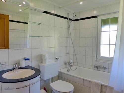 a bathroom with a toilet and a sink and a tub at Chalet Panoramablick by Interhome in Aeschi