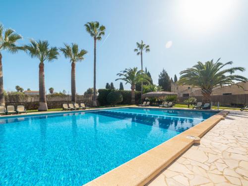 a large swimming pool with palm trees in the background at Apartment Finca Can Corritx-1 by Interhome in Muro