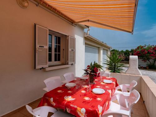 une table avec des chaises blanches et un tissu de table rouge dans l'établissement Holiday Home Dami I-2 by Interhome, à Santa-Lucia-di-Moriani