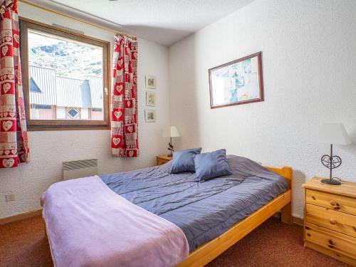 a bedroom with a bed with blue pillows and a window at Apartment Le Lac du Lou-3 by Interhome in Val Thorens