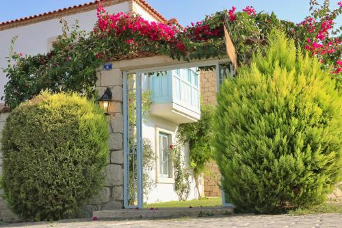 a house with bushes and flowers on the facade at Deniz Kabugu Hotel in Alacati