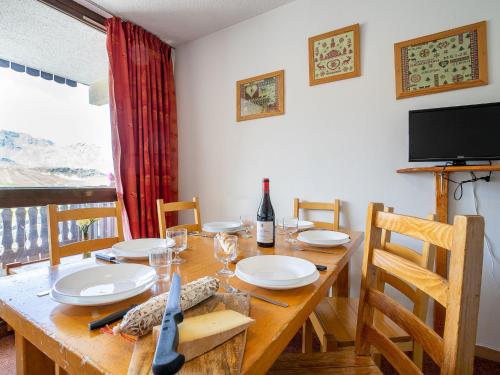 une salle à manger avec une table en bois, des chaises et une télévision dans l'établissement Apartment Lac du Lou 506 by Interhome, à Val Thorens