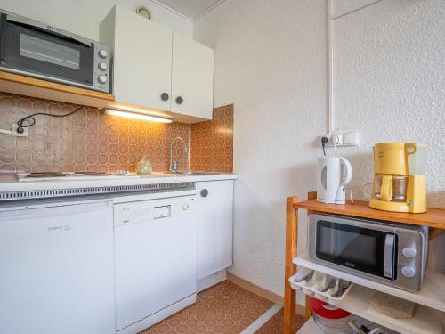 une petite cuisine avec des armoires blanches et un micro-ondes dans l'établissement Apartment Lac du Lou 506 by Interhome, à Val Thorens