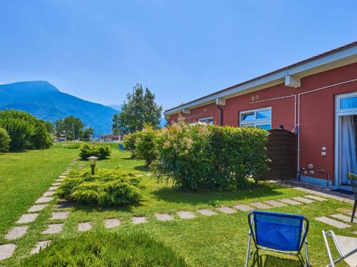 Consiglio di RumoにあるHoliday Home Gelsomino by Interhomeの赤い建物と青い椅子のある庭