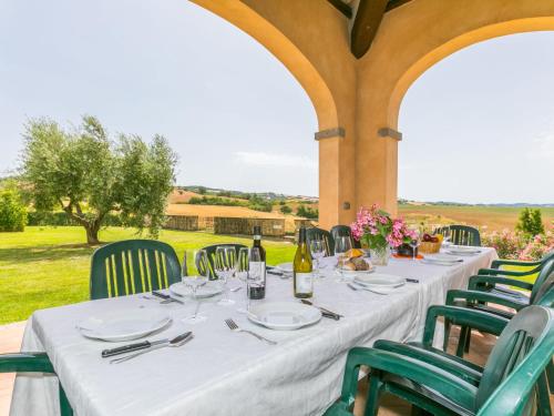 a table with a white table cloth and green chairs at Villa Casa dell'Arco by Interhome in Montemerano