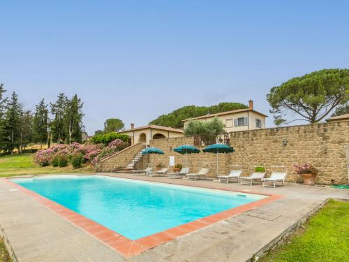 a pool with chairs and umbrellas in front of a house at Villa Casa dell'Arco by Interhome in Montemerano