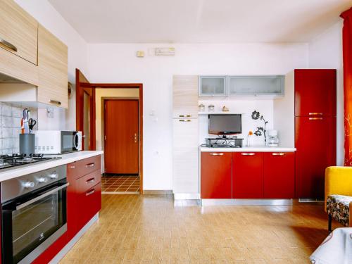 cocina con armarios rojos y fogones en Apartment Deval-2 by Interhome, en Calceranica al Lago