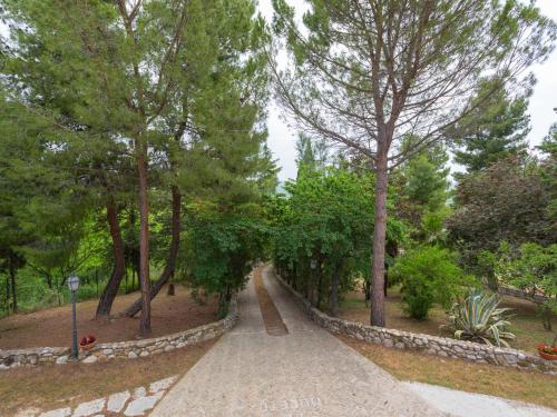 a path in a park with trees and a stone wall at Holiday Home Il Noceto by Interhome in Penne