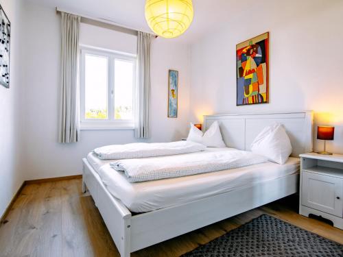 a white bedroom with two beds and a window at Holiday Home Villetta ai Pini-1 by Interhome in Calceranica al Lago