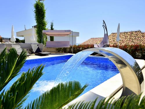 a swimming pool with a water fountain in a yard at Apartment Villa Andjelka-1 by Interhome in Trogir