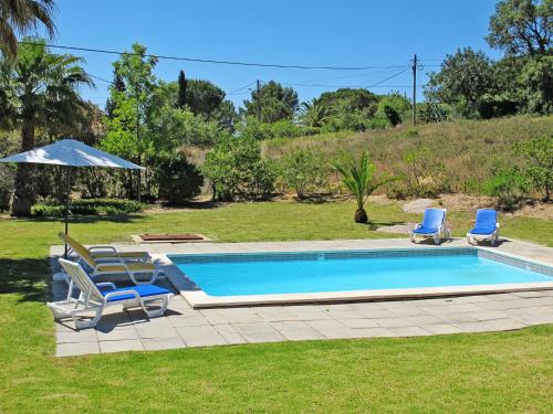 a swimming pool with two chairs and an umbrella at Holiday Home Monte Quercus - PRH100 by Interhome in Porches