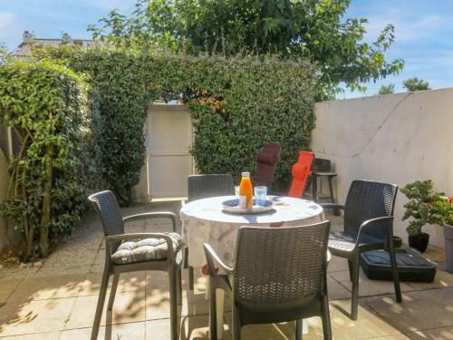 une table et des chaises assises sur une terrasse dans l'établissement Holiday Home Le Goeland Argenté by Interhome, à Les Sables-dʼOlonne