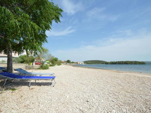 a blue bench sitting on a beach next to a tree at Apartment Ivana-5 by Interhome in Raslina