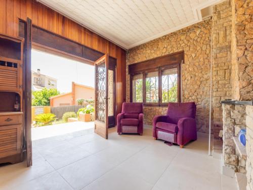 2 sillas moradas en una habitación con una pared de piedra en Holiday Home Lleida by Interhome, en Torredembarra