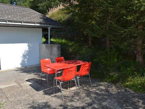 einen roten Tisch und vier Stühle auf einer Terrasse in der Unterkunft Apartment Arduus by Interhome in Gstaad