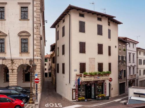 un edificio blanco en una calle de la ciudad con coches en Apartment Squisleep-2 by Interhome en San Daniele del Friuli